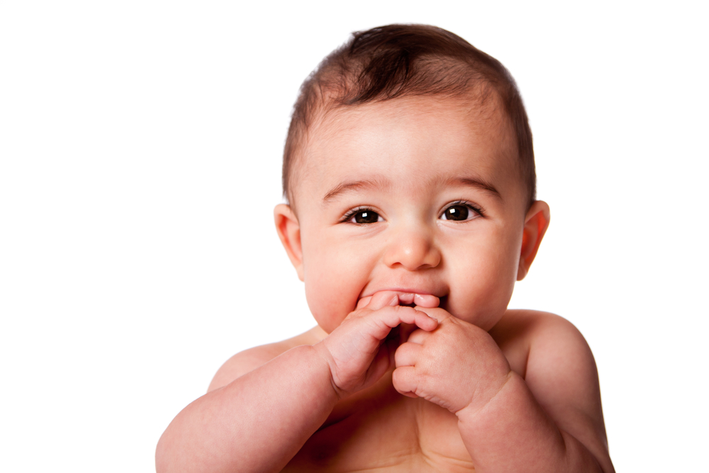 Beautiful Face of a happy cute baby infant with hands in mouth, isolated.